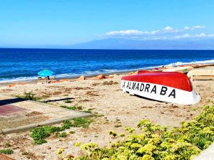 La playa de la Almadraba y una barca con el nombre del pueblo. Al fon do el mar